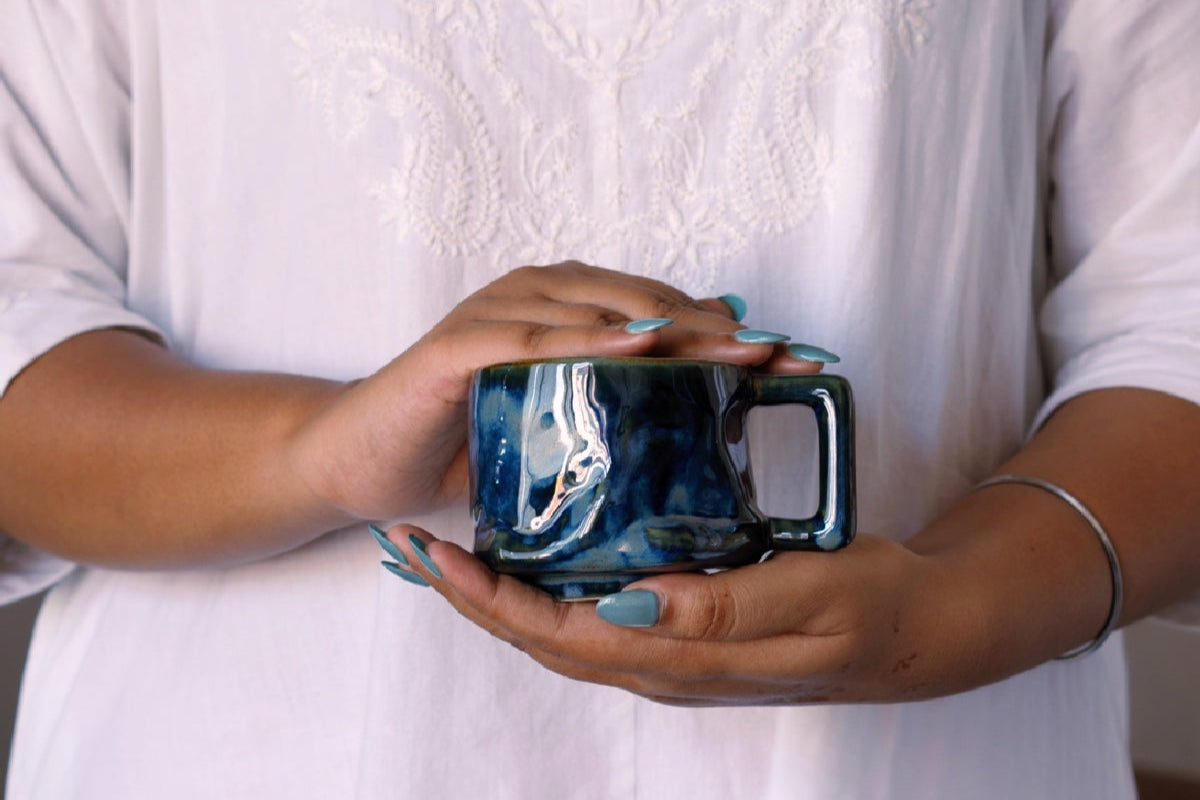 Person holding a blue mug with a white background