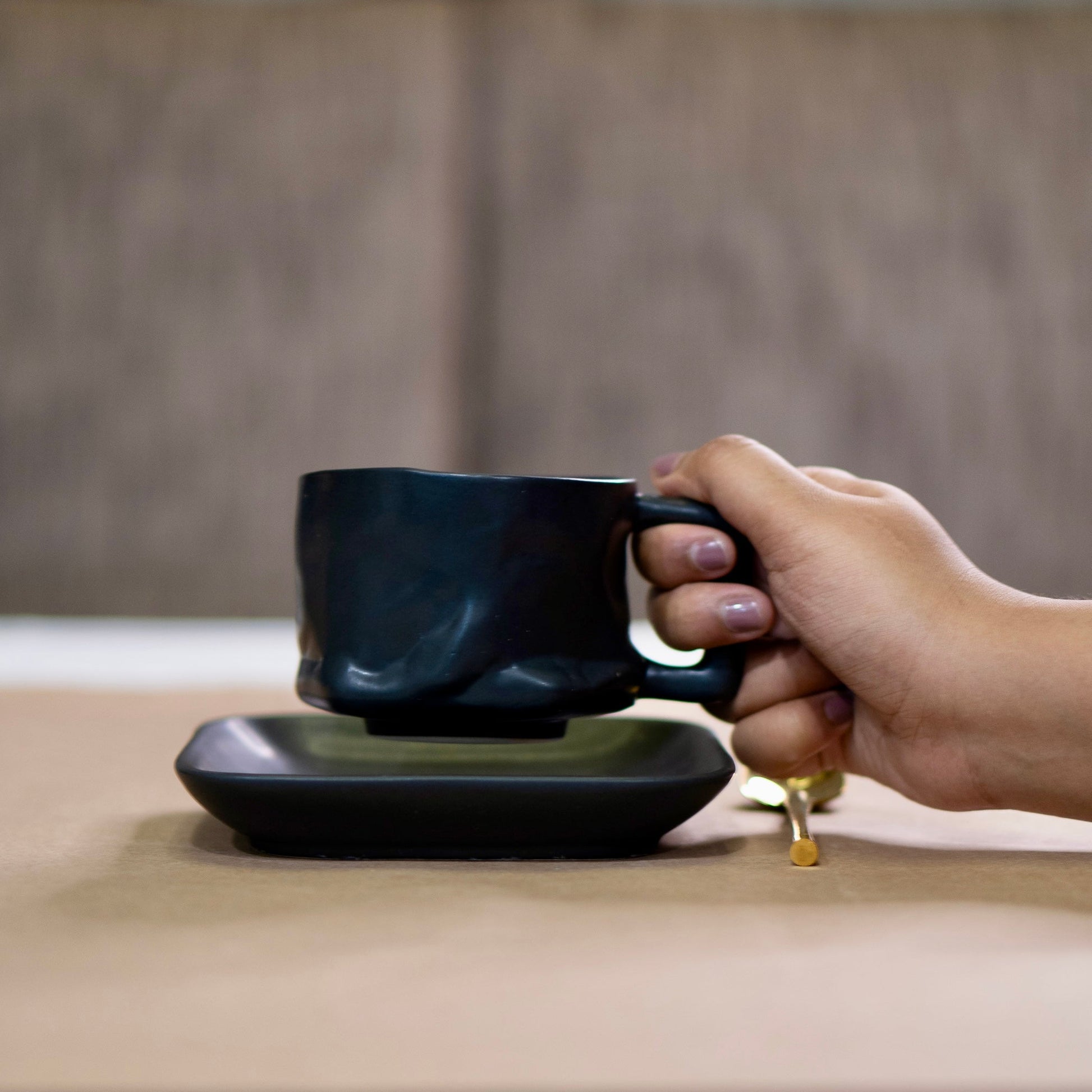 hand holding matte black yunomi mug with matte black plate